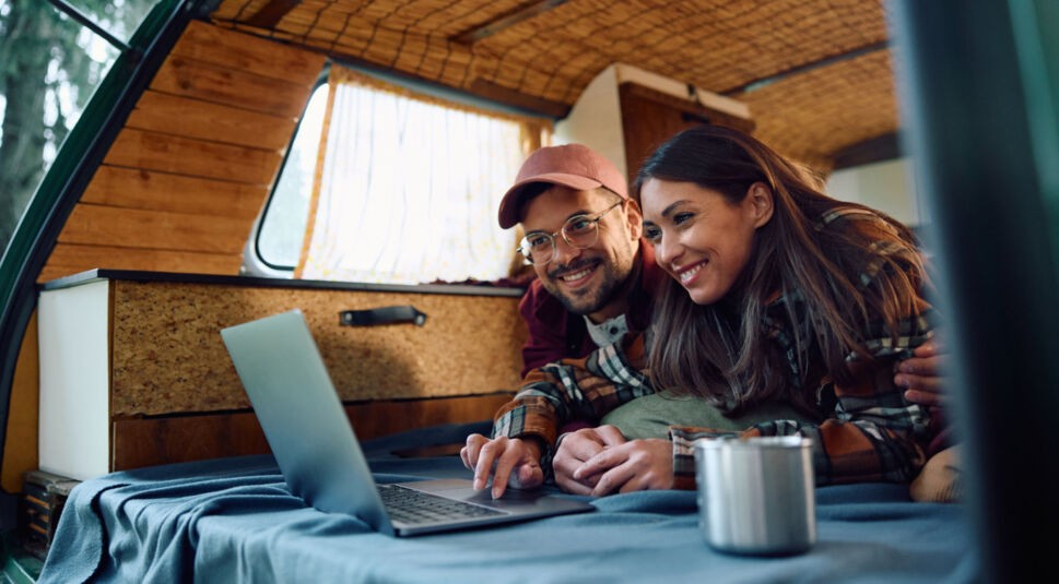 Ein Pärchen liegt im Wohnmobil und schaut auf ein Notebook.