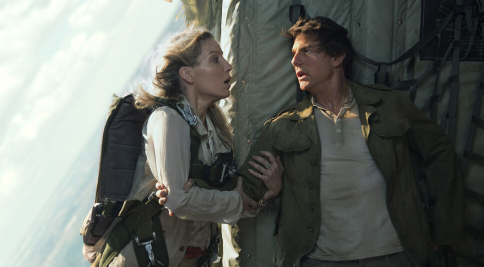 Auf dem Bild aus dem Die Mumie-Film von 2017 sind Annabelle Wallis (links) und Tom Cruise (rechts) in einer dramatischen Szene zu sehen. Beide tragen Abenteuerkleidung, Annabelle Wallis zusätzlich mit einem Fallschirmgeschirr. Die Charaktere wirken angespannt und besorgt, während sie sich gegenseitig festhalten. Die Szene spielt in einem Flugzeug mit einer dynamischen und angespannten Atmosphäre.