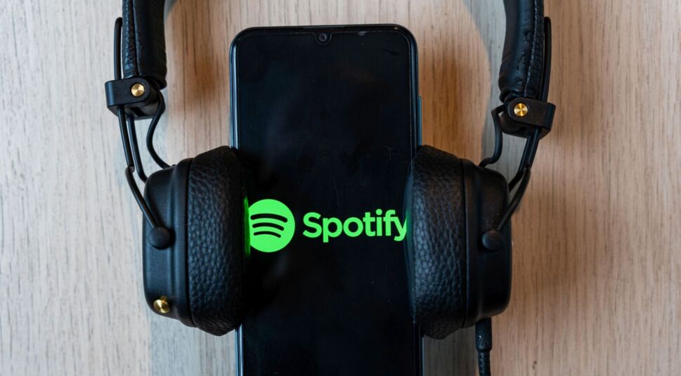 Ein Kopfhörer ist neben einem Smartphone mit dem Spotify-Logo abgebildet