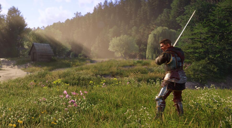 Auf dem Bild aus Kingdom Come Deliverance 2 steht ein gepanzerter Krieger mit gezogenem Langschwert auf einer blühenden Wiese. Er trägt eine detaillierte Rüstung mit Kettenhemd und dunklem Stoff. Im Hintergrund erstreckt sich eine idyllische Landschaft mit Bäumen, einer Holzhütte und Sonnenstrahlen, die durch den Wald fallen. Die Szenerie vermittelt eine ruhige, aber zugleich spannende Atmosphäre, als würde sich der Krieger auf einen Kampf vorbereiten. (Kingdom Come Deliverance 2 Tipps)