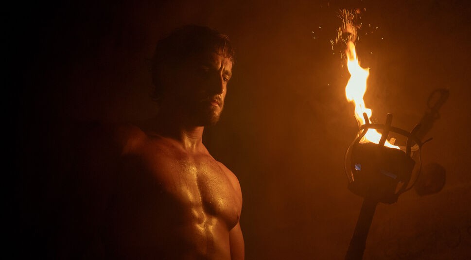 Auf dem Bild in dem Artikel zu den Oscar Filmen 2025, die bei GigaTV verfügbar sind, ist eine Szene aus Gladiator II zu sehen. Ein muskulöser Mann steht mit ernstem Blick in einem dunklen Raum, nur erleuchtet vom flackernden Licht einer großen Fackel, die er hält. Der warme, orangefarbene Schein betont seine angespannte Mimik und die düstere Atmosphäre. Die Szene wirkt intensiv und kraftvoll.