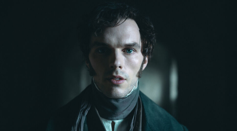 Auf dem Bild in dem Artikel zu den Oscar Filmen 2025, die bei GigaTV verfügbar sind, ist eine Szene aus Nosferatu – Der Untote zu sehen. Ein blasser Mann mit dunklen Locken und blauen Augen blickt mit leicht geöffnetem Mund direkt in die Kamera. Er trägt Kleidung bestehend aus einem dunklen Mantel und einem hohen Halstuch. Die Beleuchtung ist düster, mit einem schwachen Lichtschein im Hintergrund, was eine unheimliche und geheimnisvolle Atmosphäre schafft.