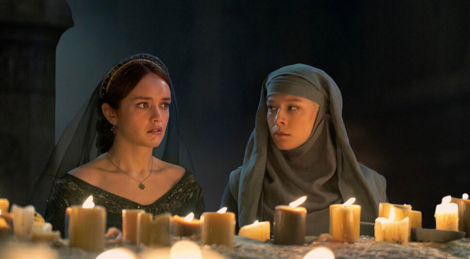 In dieser Szene aus House of the Dragon Staffel 2 sitzen Alicent Hohenturm, gespielt von Olivia Cooke, und Rhaenyra Targaryen, dargestellt von Emma D’Arcy, schweigend vor einem Altar mit brennenden Kerzen. Beide wirken angespannt und nachdenklich – ein stiller, aber intensiver Moment, der die Spannung für House of the Dragon Staffel 3 weiter aufbaut.