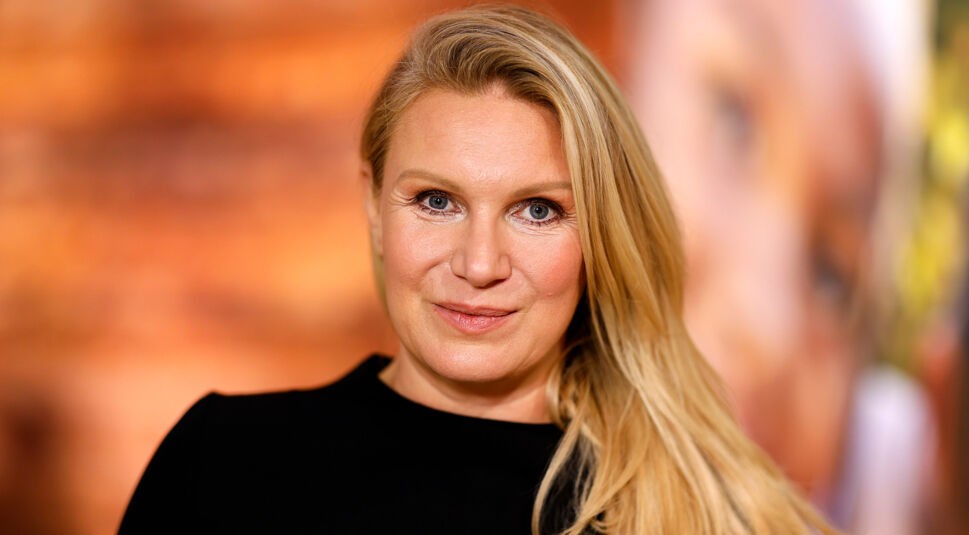 Auf dem Bild in dem Artikel zu den Let's Dance Gewinner:innen ist Magdalena Brzeska zu sehen. Sie trägt ein elegantes schwarzes Oberteil und hat ihre langen, blonden Haare locker über eine Schulter gelegt. Ihr Gesichtsausdruck ist freundlich und selbstbewusst, während sie direkt in die Kamera blickt. Der Hintergrund ist warm und unscharf gehalten, was die Person in den Mittelpunkt rückt.