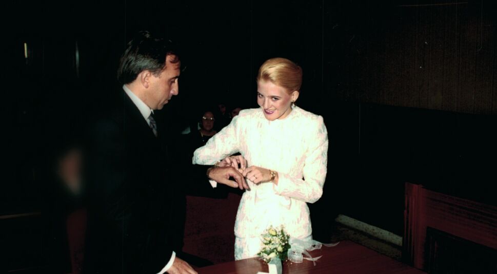 Angi - (K)eine perfekte Mörderin: Eine blonde Frau im weißen Kleid steckt einem Mann in Anzug während einer Trauung den Ehering an.