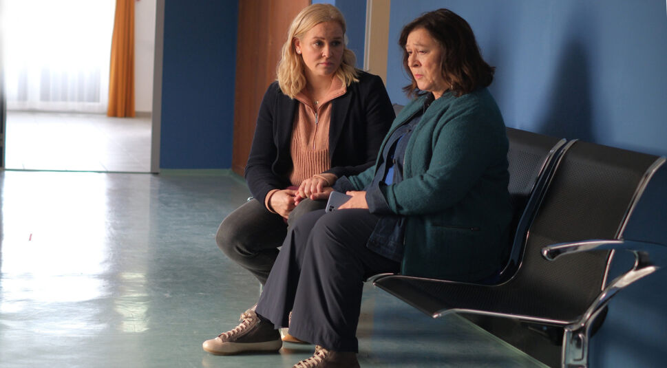 In einem Krankenhausflur sitzen Lena und Eva Lorenz nebeneinander.