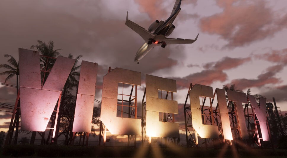 Auf diesem Bild aus GTA VI ist ein riesiger, rostiger Schriftzug „VICE CITY“ zu sehen, der in der Abenddämmerung von Scheinwerfern beleuchtet wird. Über dem Schild fliegt ein Flugzeug tief hinweg durch den dramatisch gefärbten Himmel, während im Hintergrund Palmen und Industriebauten angedeutet sind. Die Szene vermittelt das ikonische, tropisch-urbane Flair von GTA VI.