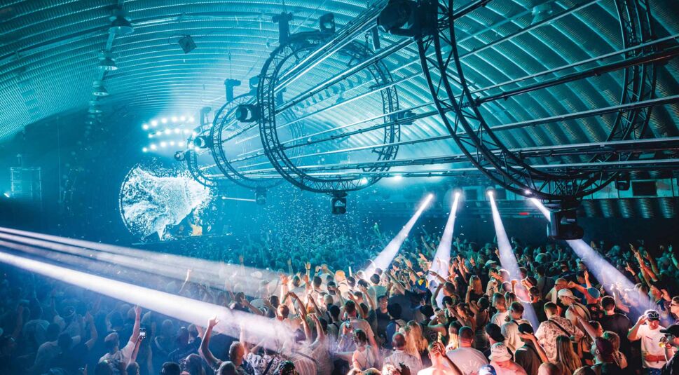 Diese Szene im Zusammenhang mit parookaville tickets zeigt eine der Indoor-Bühnen des Parookaville-Festivals mit dicht gedrängtem Publikum unter einer futuristisch beleuchteten Kuppel.