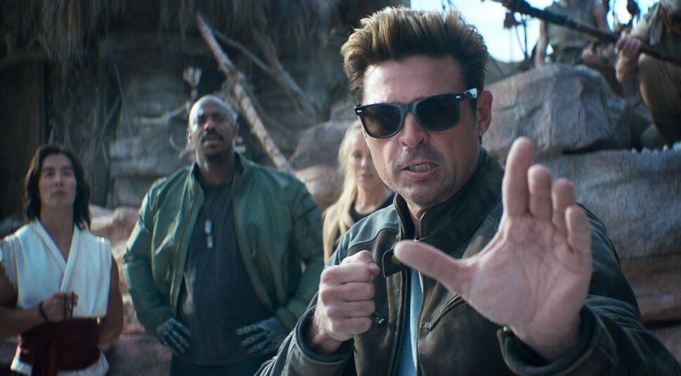 Auf diesem Bild zu spiele-verfilmungen 2025 sieht man eine Szene aus „Mortal Kombat 2“: Im Vordergrund steht Karl Urban als Johnny Cage mit Sonnenbrille und kampfbereiter Pose. Links von ihm sind Ludi Lin als Liu Kang, Mehcad Brooks als Jax Briggs und Jessica McNamee als Sonya Blade zu sehen.