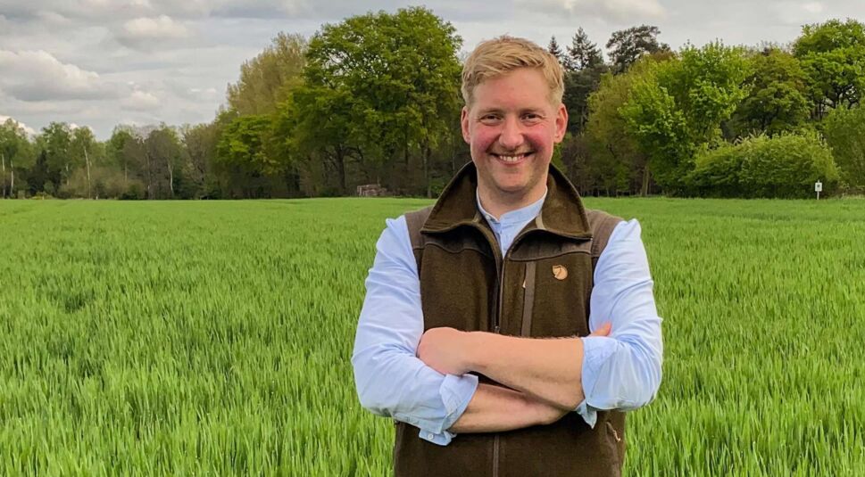 Bei Bauer sucht Frau 2025 steht Kandidat Daniel mit verschränkten Armen in einem grünen Getreidefeld. Mit Weste und Hemd blickt er freundlich in die Kamera vor bewaldetem Hintergrund.