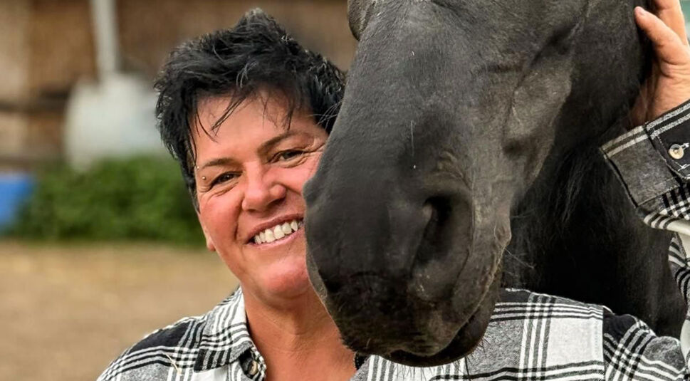 Bei Bauer sucht Frau 2025 steht Kandidatin Simone in kariertem Hemd lachend neben einem schwarzen Pferd, das sie liebevoll streichelt. Die Szene wirkt herzlich und vertraut.
