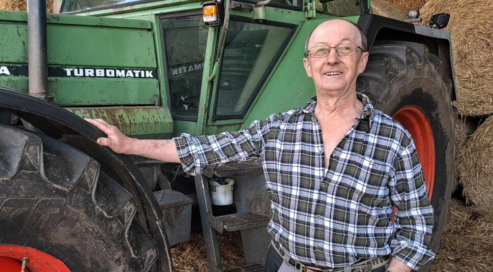 Bei Bauer sucht Frau 2025 steht Kandidat Walter im karierten Hemd neben einem grünen Traktor in seiner Scheune.