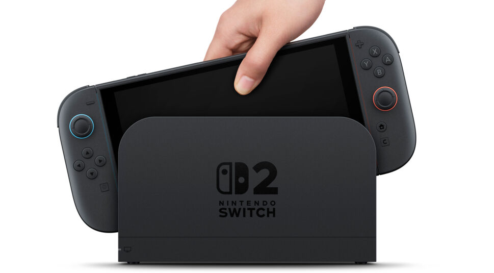 Auf diesem offiziellen Bild wird die neue Nintendo Switch 2 in eine Docking-Station eingesetzt. Eine Hand führt die Konsole in die Station mit dem Logo „Nintendo Switch 2“ ein. Das moderne Design hebt sich dezent vom Vorgänger ab und veranschaulicht die Switch 2 vs. Switch 1 Unterschiede im Bereich Hardware und Verarbeitung.