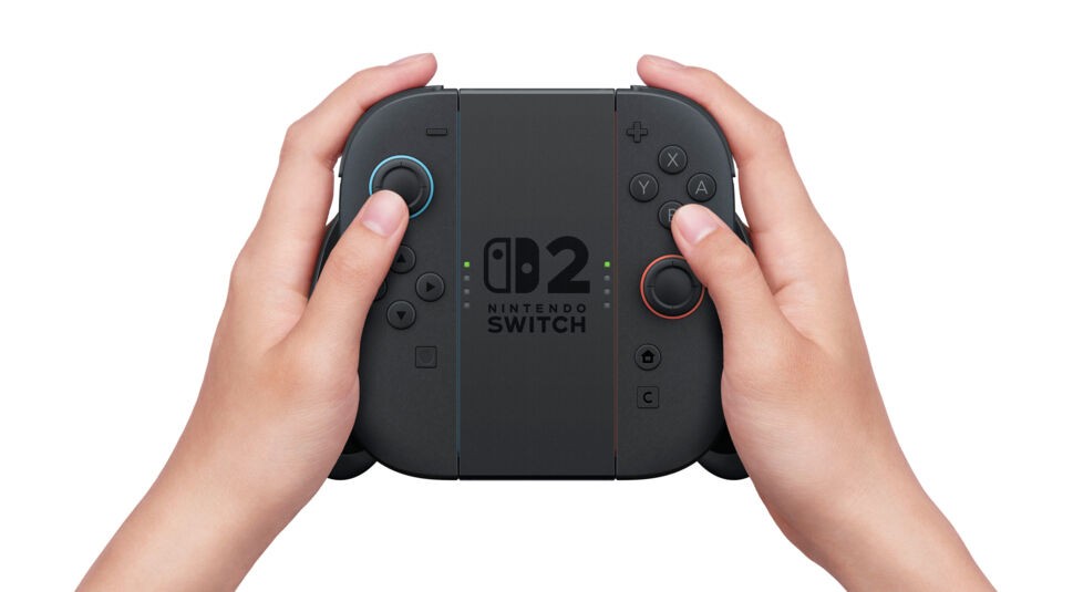 Das Bild zeigt die neue Halterung der Nintendo Switch 2, in der zwei Joy-Con-Controller als klassischer Controller verbunden sind. Beide Hände halten das Gamepad, mittig ist das „Nintendo Switch 2“-Logo zu sehen. Die geänderte Halterung unterstreicht die Switch 2 vs. Switch 1 Unterschiede in puncto Flexibilität, Form und Handhabung im Controller-Modus.