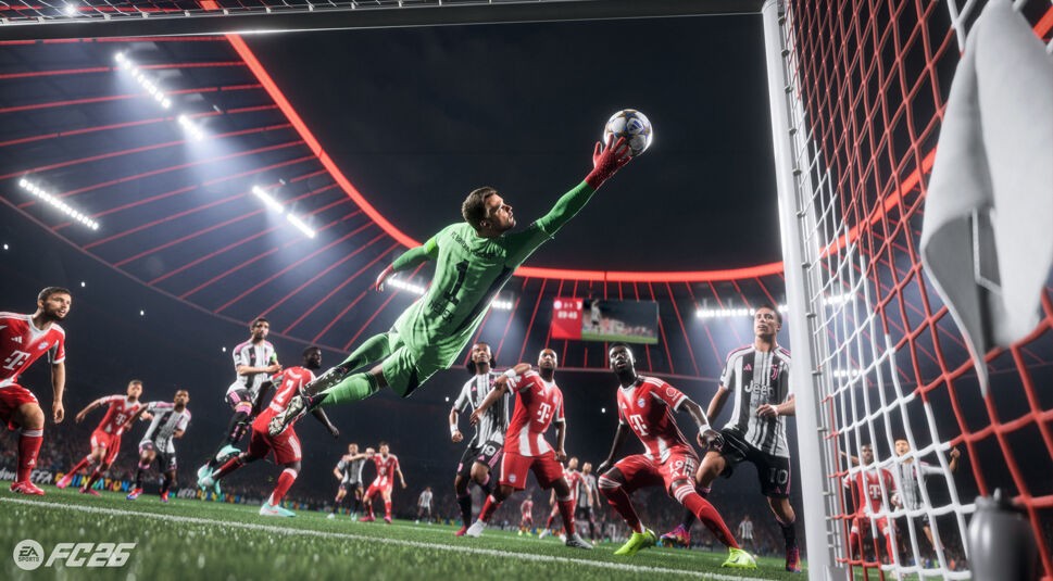 In diesem Screenshot aus „EA Sports FC 26“ fliegt Torwart Manuel Neuer im grünen Trikot von Bayern München spektakulär durch die Luft, um einen Schuss abzuwehren. Um ihn herum kämpfen Spieler von Bayern und Juventus im Strafraum. Die Szene im rot leuchtenden Stadion ist spannungsgeladen und voller Dynamik.