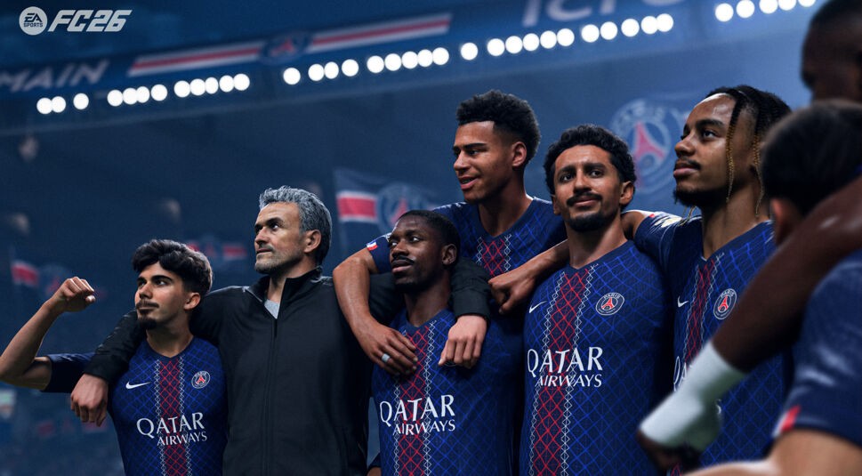 Auf diesem Screenshot aus „EA Sports FC 26“ ist Trainer Luis Enrique gemeinsam mit mehreren Spielern seines Teams Paris Saint-Germain zu sehen. Die Gruppe steht Schulter an Schulter im Stadion, lächelt und blickt stolz nach vorn. Die Szene vermittelt Teamgeist und Siegesstimmung vor jubelnden Fans im Hintergrund.