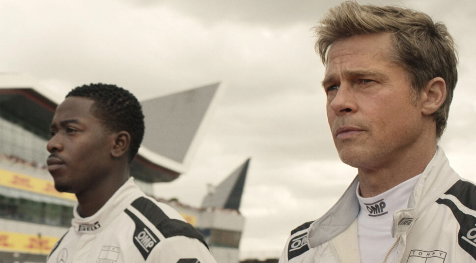 In den GigaTV-Highlights im August ist eine Szene aus dem Film F1 zu sehen, in der Brad Pitt als Ex-Rennprofi in einem weißen Rennanzug neben einem jungen Fahrer steht.