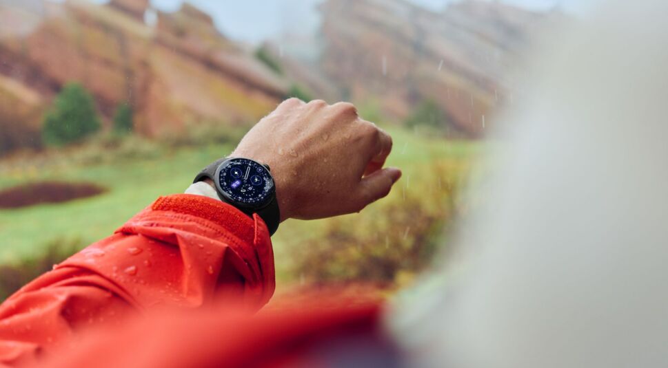 Mann schaut im Regen auf die Pixel Watch 4 an seinem Handgelenk.