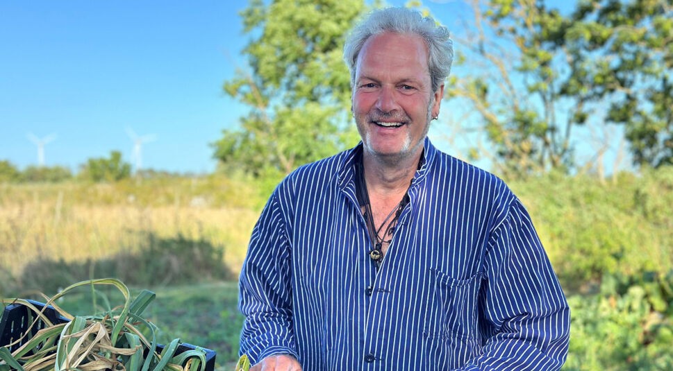 Auf dem Bild zu Bauer sucht Frau International 2026 steht ein Mann mit gestreiftem Hemd auf einem Feld.