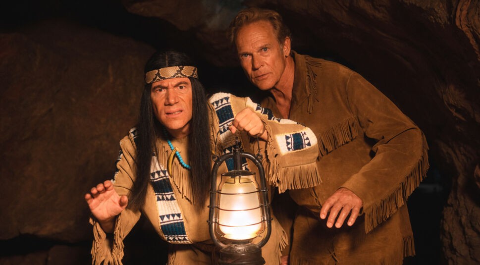 Auf diesem Bild zur Das Kanu des Manitu Kritik schleichen Michael Bully Herbig als Abahachi und Christian Tramitz als Ranger durch eine dunkle Höhle. Abahachi hält eine leuchtende Petroleumlampe vor sich, beide schauen aufmerksam und leicht angespannt nach vorn. Die Szene wirkt geheimnisvoll und spannungsgeladen.