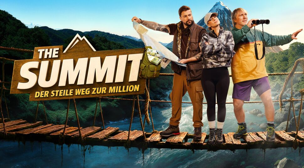 Auf dem Bild zur Show The Summit ist die dritte Gruppe mit Felix von Jascheroff, Julia Römmelt und Ansgar Brinkmann zu sehen. Felix zeigt mit ernster Miene auf eine aufgefaltete Karte, während Julia mit verschränkten Armen danebensteht und ruhig wirkt. Ansgar trägt eine Windjacke und hält ein Fernglas in Richtung des Bergpanoramas. Die Gruppe steht auf einer alten Hängebrücke über einem Wildfluss.