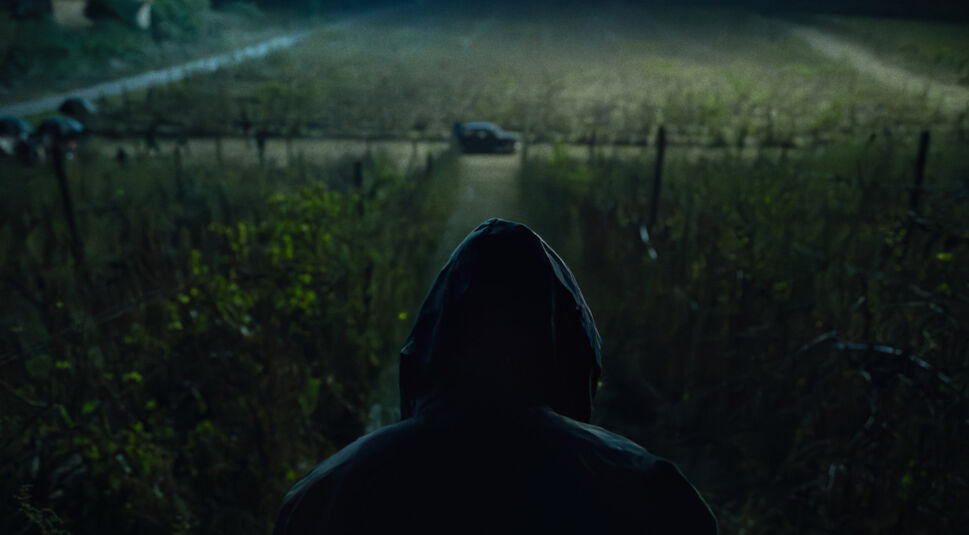 Ein Mann schaut auf der Ferne auf ein Auto, das nachts in der Feldmark parkt.