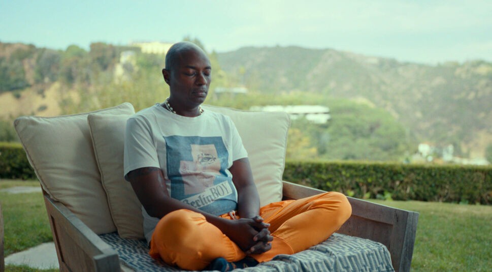 Durek Verrett sitzt im Schneideseit auf einem breiten Sessel im Freien und hat die Augen geschlossen.