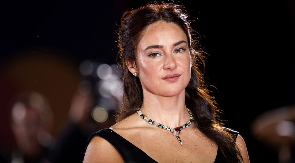 Auf diesem Bild zur Count My Lies-Serie ist Schauspielerin Shailene Woodley in einem eleganten, schwarzen Kleid mit funkelnder Schlangenkette zu sehen. Sie blickt ruhig und selbstbewusst in die Kamera. Der Hintergrund ist unscharf und deutet auf ein Event hin, aber der Fokus liegt klar auf ihrer Erscheinung.