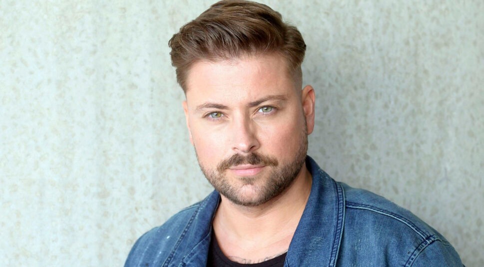 Auf diesem Porträt zur GZSZ-Besetzung ist Felix von Jascheroff zu sehen. Er trägt eine Jeansjacke über einem schwarzen Shirt und schaut in die Kamera.