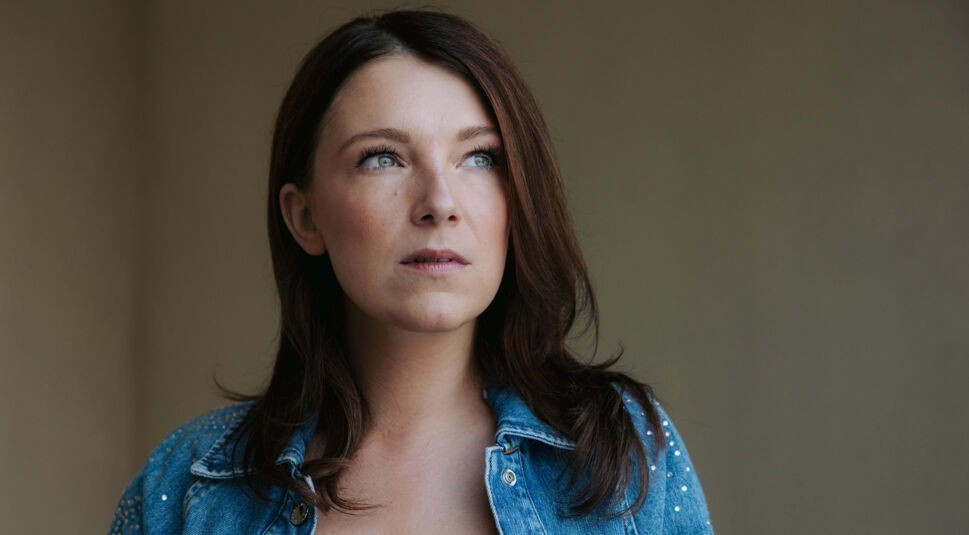 Das Bild zur GZSZ-Besetzung zeigt Iris Mareike Steen. Sie trägt eine Jeansjacke mit kleinen Glitzersteinen und blickt zur Seite.