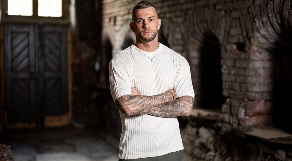 Serkan Yavuz steht auf dem Bild zu „Das große Promi-Büßen“ 2025 mit verschränkten Armen und ernstem Gesichtsausdruck.