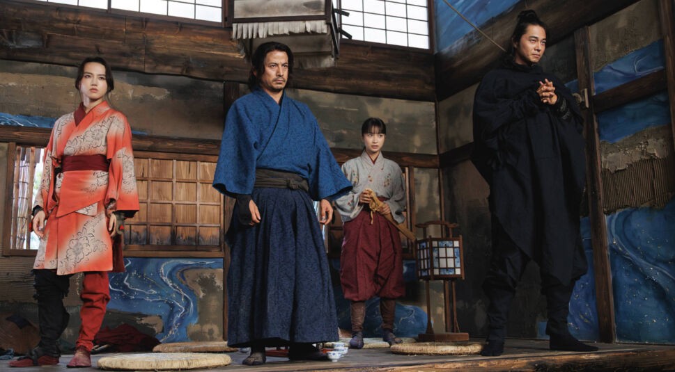 Szenenbild aus der Serie Last Samurai Standing: Vier Personen in traditioneller japanischer Kleidung stehen in einem hölzernen Raum mit Shoji-Fenstern.