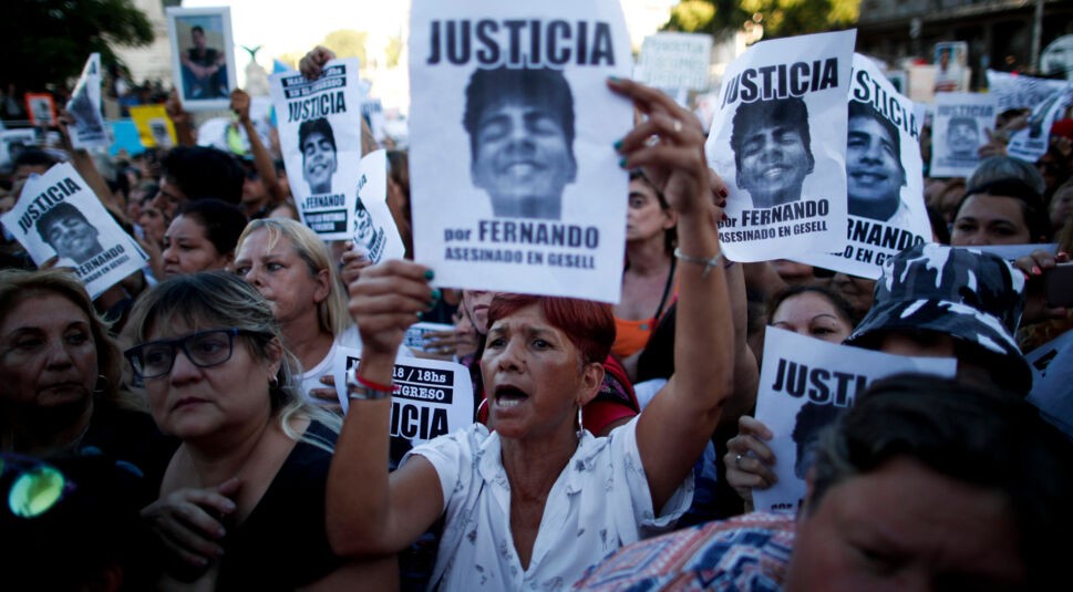 Menschen protestieren vor dem argentinischen Parlamentsgebäude und halten Plakate hoch.