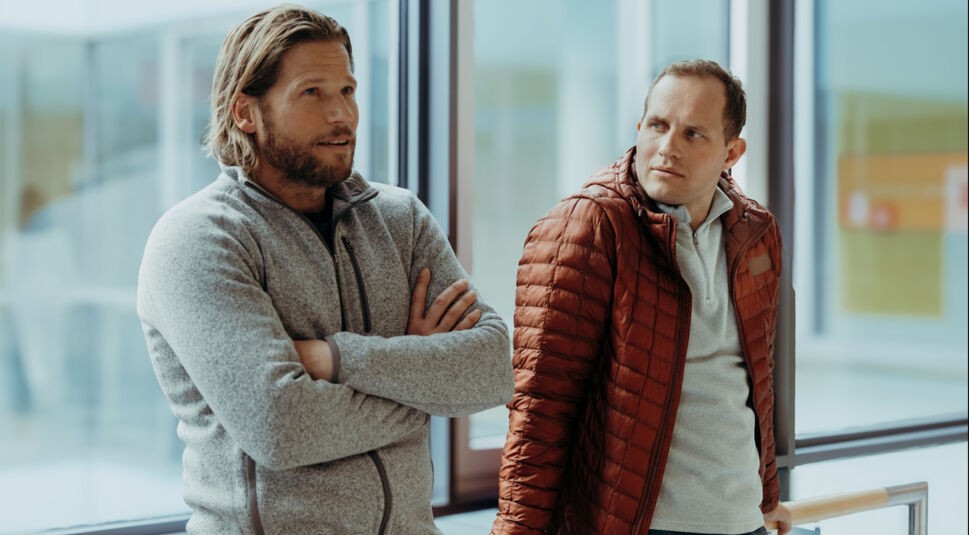 Markus Kofler (Sebastian Ströbel) und sein Halbbruder Jan Fugain (Arne Löber) stehen nebeneinander und unterhalten sich.
