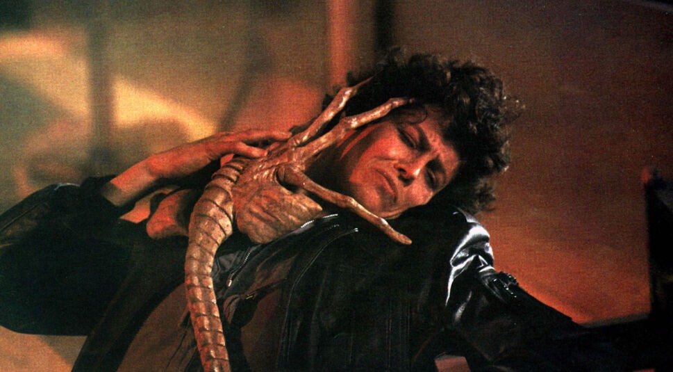 Auf dem Bild aus Aliens ist Sigourney Weaver als Ellen Ripley zu sehen, während sich ein Facehugger außerirdisch und bedrohlich an sie klammert. Ihr Gesicht zeigt Anspannung und Entschlossenheit – sie gilt als eine der prägendsten Actionhelden der 80er und 90er, die weibliche Stärke im Sci-Fi-Genre neu definierte.