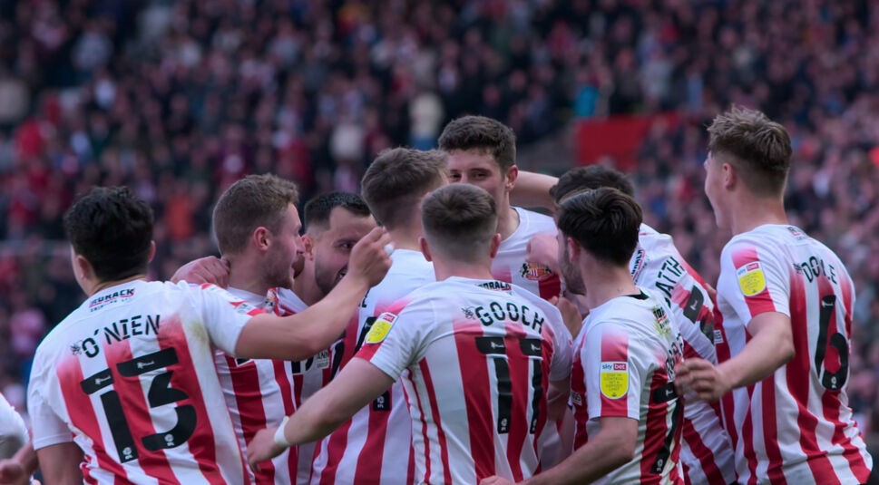 In der Doku-Serie „Sunderland 'Til I Die“ begleiten Zuschauer hautnah den englischen Traditionsklub. Auf dem Bild feiern mehrere Spieler von Sunderland in ihren rot-weiß gestreiften Trikots einen emotionalen Treffer. Die Szene wirkt mitreißend und authentisch – ein perfektes Beispiel für mitreißende Fußball-Serien mit echtem Stadionfeeling.