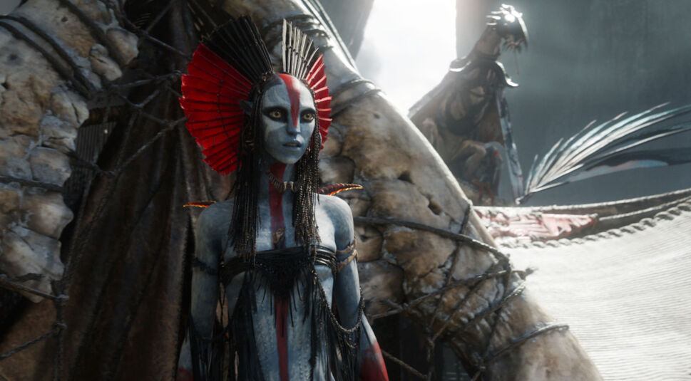 Im Bild aus Avatar: Fire and Ash ist die neue Figur Varang zu sehen, gespielt von Oona Chaplin. Sie steht ernst und aufrecht vor einer zeremoniellen Kulisse, geschmückt mit rotem Kopfschmuck und Kriegsbemalung. Ihre Präsenz wirkt autoritär und angriffslustig – eine zentrale Szene für die Avatar: Fire and Ash-Kritik.