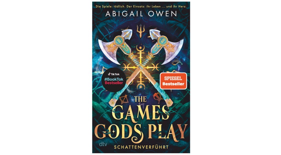 Das Cover von Band 1 der Buchreihe The Games Gods Play zeigt zwei gekreuzte Äxte mit goldenen Ornamenten vor einem mystischen, dunkelblauen Hintergrund mit Symbolen. Oben steht der Name der Autorin Abigail Owen, unten der Titel Schattenverführt. Das Buch ist als SPIEGEL Bestseller ausgezeichnet. Ideal zur Darstellung der The Games Gods Play-Reihenfolge.