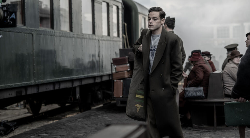 Douglas Kelley (Rami Malek) steht an einem Bahnsteig neben einem Zug.