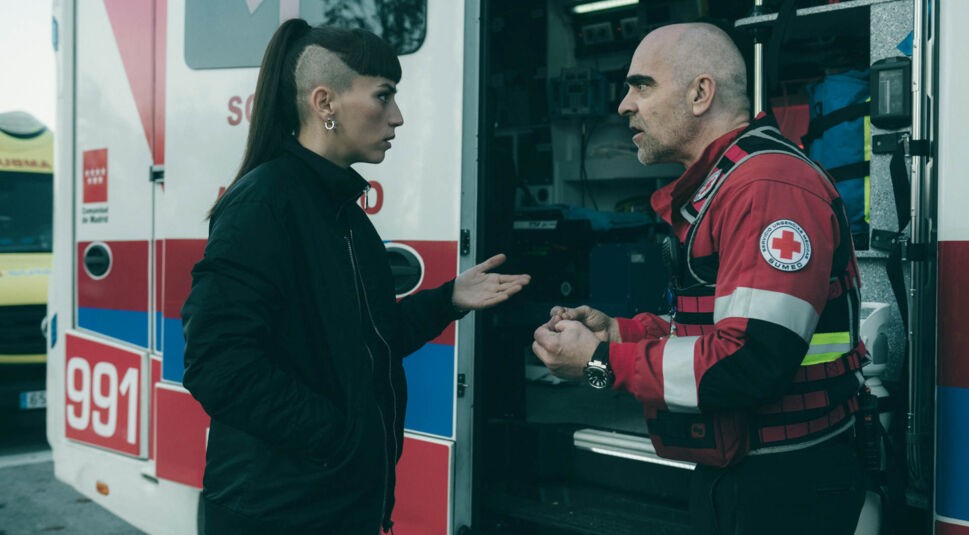 Julia und Salvador sprechen vor einem Rettungswagen miteinander.