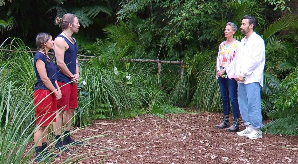 Auf dem Bild in dem Artikel zum Dschungelcamp 2026 sind die Moderator:innen und zwei Kandidat:innen bei der Prüfung zu sehen.