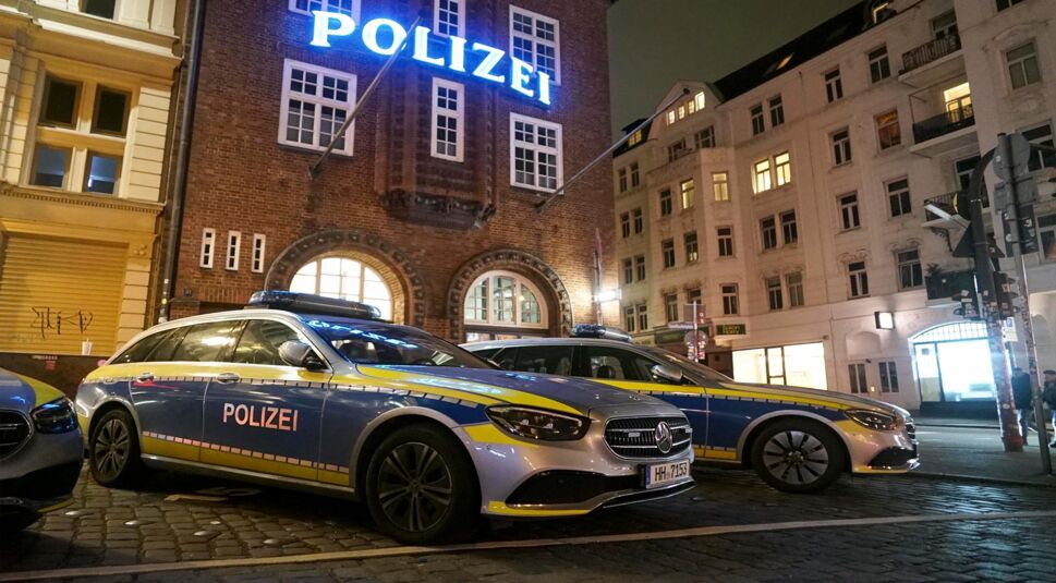 Polizeifahrzeuge stehen nachts vor der beleuchteten Davidwache auf der Hamburger Reeperbahn. 