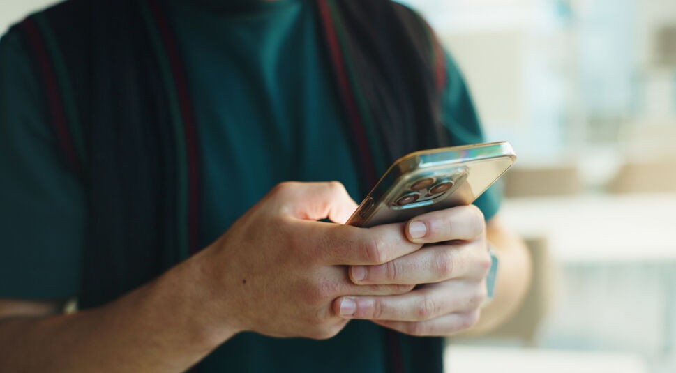 Auf dem Bild zum Thema Datenvolumen sparen iPhone sind die Hände einer Person zu sehen, die ein Smartphone mit transparenter Hülle hält und bedient. Der Fokus liegt auf dem Gerät, während Gesicht und Hintergrund unscharf bleiben. Die ruhige, helle Alltagsszene wirkt konzentriert und eignet sich für Tipps zur mobilen Datennutzung.