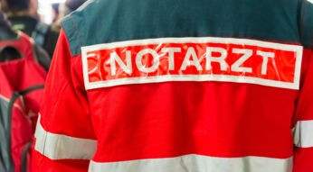 Ein Notarzt, dessen Jacke mit Aufschrift man von hinten sieht.