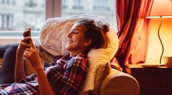 Frau tippt zu Hause am iPhone.