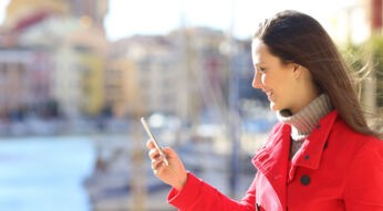 Frau im roten Mantel schaut auf ihr Smartphone