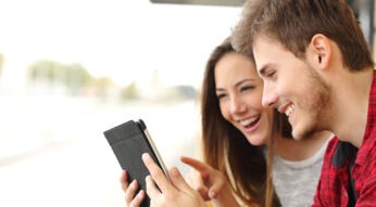 Junges Paar spielt draussen auf dem iPad