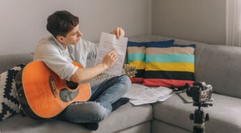 Junger Mann mit Gitarre filmt sich selbst