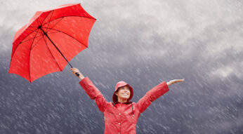 Frau mit Regenschirm lacht über den Regen
