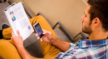 Ein Mann scannt einen QR-Code aus einer Zeitung ab.